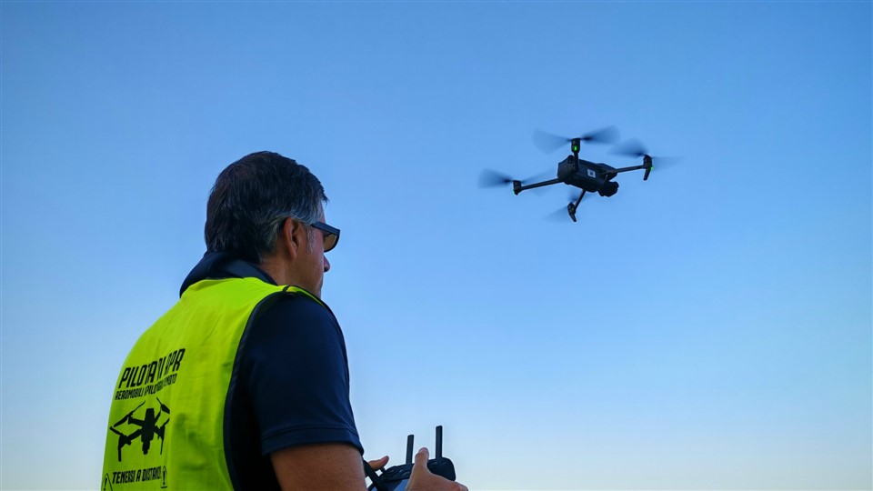 Pilota di APR certificato durante un volo di ispezione con drone, in sicurezza da terra
